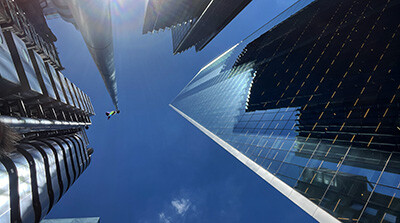 An image looking up between towering buildings at a dark blue sky. Possibly using a polarising filter. Printed on the Hemp fibre based fine art paper.